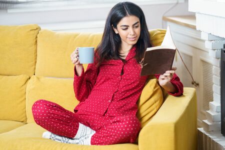 Woman at home having tea and readingの写真素材