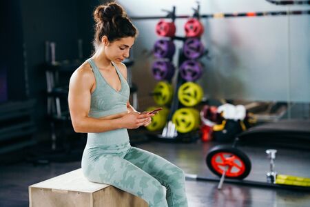 Woman consulting her training on her smartphone sitting in a jump box