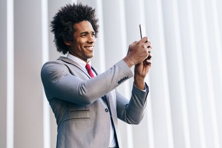 Black Businessman using a smartphone near an office buildingの写真素材