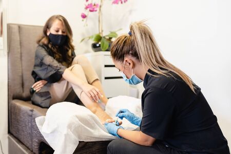 Beautician giving a pedicure painting her clients nails in a beauty centre.の写真素材