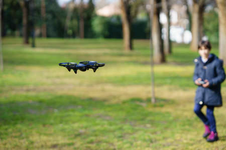 Nine-year-old girl operating toy drone flying by remote control