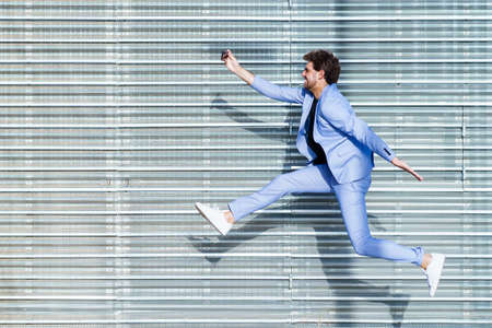 Man wearing a suit makes a selfie with a smartphone while jumpingの写真素材