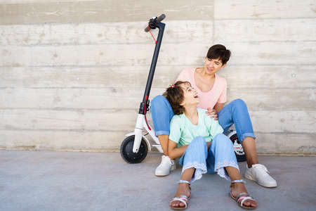 Mother and daughter sitting on an electric scooterの写真素材
