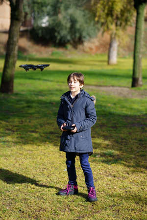 Nine-year-old girl operating toy drone flying by remote control