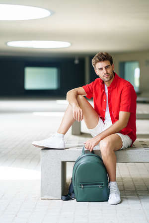 Male student sitting on a college campus bench