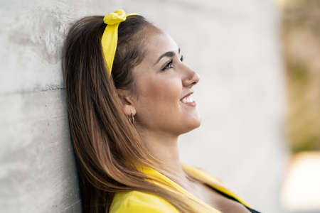Young woman wearing a yellow jacket and headband smiling.