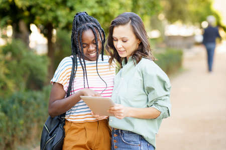 Two multiethnic women consulting something on a digital tablet.