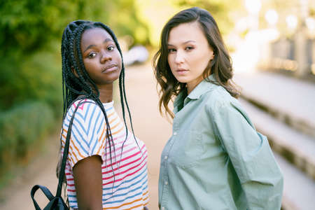 Two Multiethnic women looking at camera together on the street.