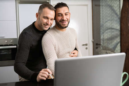 Romantic Gay couple working together at home with their laptops.