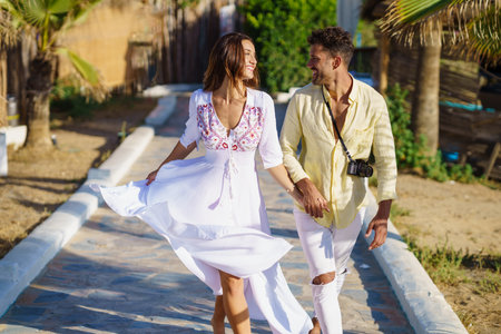 Loving couple walking along a wooden path towards the beach in a coastal area.の写真素材