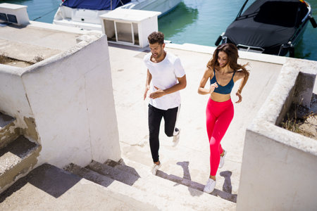 Athletic couple training hard by running up stairs together outdoors.