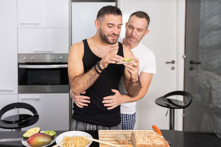 Gay couple cooking healthy vegan food together at home.
