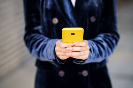 Business woman wearing blue suit using smartphone in an office building.の写真素材