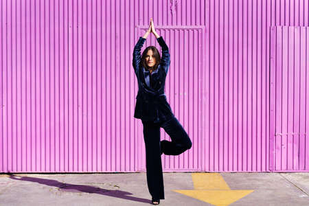 Woman wearing blue suit posing near pink shutter.