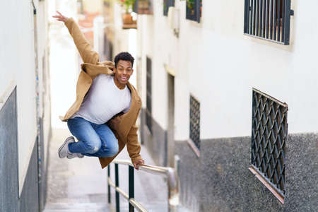 Young black man jumping for joy over a handrail in the street.の写真素材