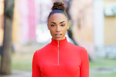 Young black woman in red dress posing on a street with colorful walls