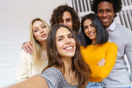 Multi-ethnic group of friends taking a selfie together while having fun outdoors.の写真素材