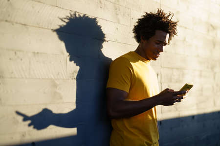 Black man consulting his smartphone while resting from his workout.