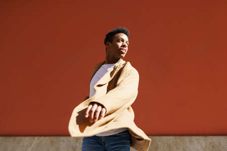 Young Cuban man dancing on red urban wall.の写真素材