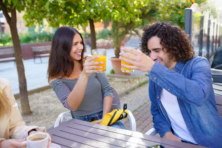 Couple of friends toasting while having a drink with their multi-ethnic group of friendsの写真素材