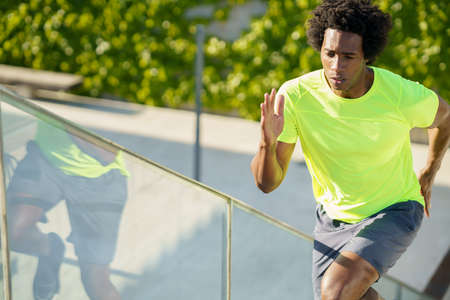 Black man running upstairs outdoors. Young male exercising.