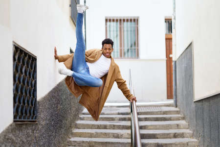 Young black man jumping for joy over a handrail in the street.の写真素材