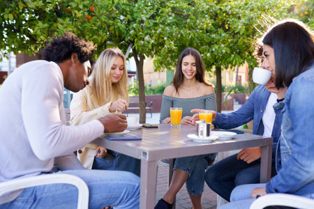 Multi-ethnic group of friends having a drink together in an outdoor bar.の写真素材