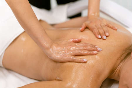 Woman receiving a back massage with massage candle oil.