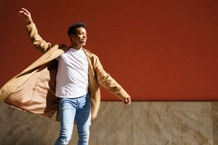 Young black man dancing on red urban wall.の写真素材