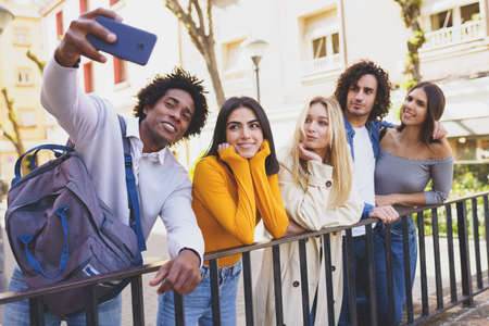 Black man with afro hair taking a smartphone selfie with his multi-ethnic group of friends.の写真素材