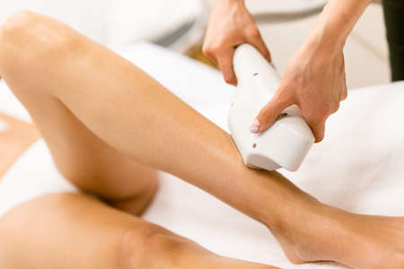 Woman receiving legs laser hair removal at a beauty center.の写真素材
