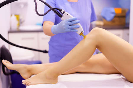Woman receiving legs laser hair removal at a beauty center.の写真素材
