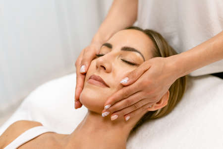 Middle-aged woman having a head massage in a beauty salon.の写真素材