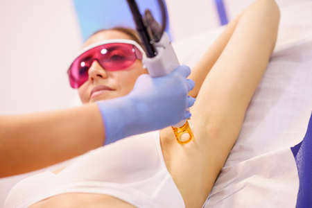 Woman receiving underarm laser hair removal at a beauty center.の写真素材
