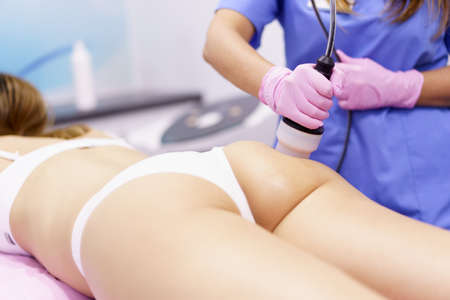 Woman receiving anti-cellulite treatment with radiofrequency machine in a beauty center.