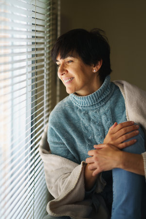 Happy middle-aged woman smiling while looking out the window.