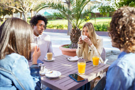 Multi-ethnic group of friends having a drink together in an outdoor bar.の写真素材