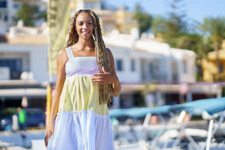 Mixed woman walking along a seaport wearing a nice summer dress.
