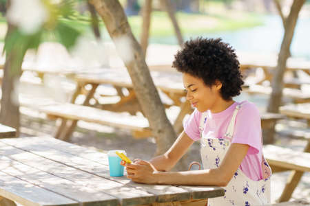 Young African-American woman sitting in a break area at her university drinking a beverage from a...