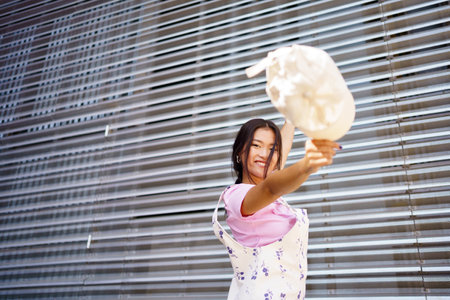 Happy young Asian female looking at camera smiling with happiness. Chinese student woman wearing casual clothes and cap.の写真素材