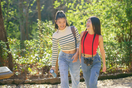 Positive young Asian female friends in casual outfits smiling and speaking about life while...