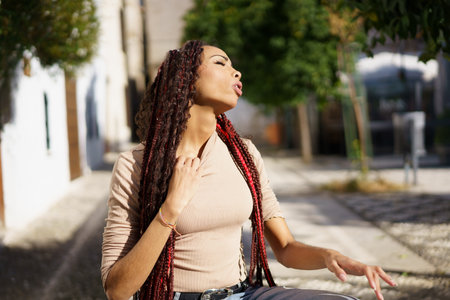 In a vibrant urban setting, bathed in golden sunlight, a confident young woman with long braids...