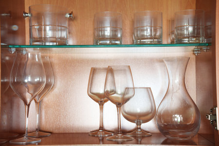 Sophisticated wine setup on rustic wooden shelves, Tasteful arrangement of wine glasses and carafe illuminated softly on wooden shelving unitの写真素材