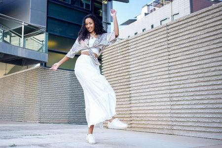 Young woman in white skirt striking joyful midspin on concrete plaza, flowing skirt, lace top,...