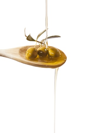 Olive oil jet over a olive branch in a wooden spoonの写真素材
