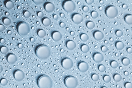 Voluminous water drops on a blue and smooth surfaceの写真素材