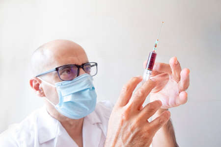 doctor with a syringe of blood in his hand tapping out airの写真素材