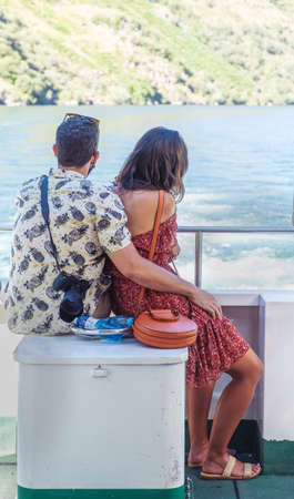 tourist couple on holiday enjoying a boat ride looking at the landscape overboard vertical