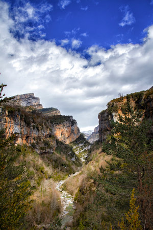 mountain scenery with a river flowing through it on a sunny day with cotton clouds, Anisclo canyon on the Bellos river, Huesca Pyrenees, Spainの写真素材