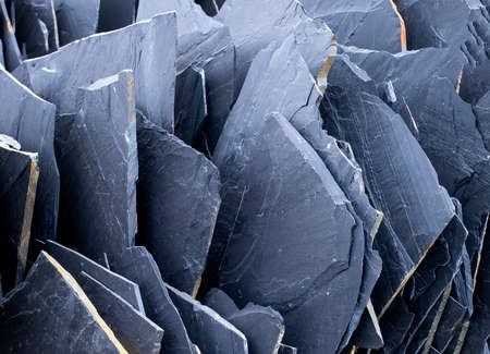 texture of black slate slabs in a quarry or pit, building material, black stone, dark gray, black...